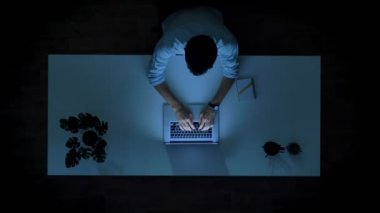 Üst adam dizüstü bilgisayarda yazarak office vibes zaman geçirerek ve çalışma saatleri içinde oyun ışık harcama zaman atlamalı vurdu