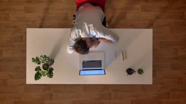 Décryptage du haut vers le bas le jour passe du matin au soir, mouvement des rayons du soleil, homme d'affaires endormi sur la table avec allumé ordinateur portable — Video