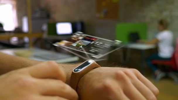 Futuristic device on a mans hand, a hologram, smart watch office in the background — Stock Video