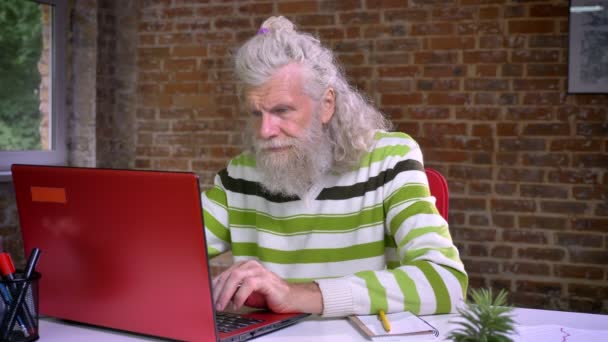 疲倦的工作的老白种男性是打呵欠和覆盖他的头用他的手和放松, 而坐在布朗砖办公室 — 图库视频影像