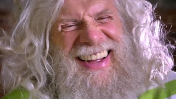 Primer plano retrato de la abuela caucásica, impresionante barba blanca larga y el pelo, riendo felizmente de la cámara en movimiento, ladrillo de fondo moderno — Vídeo de stock
