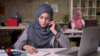 Memnun Arap kadın, dinleme ve onun Masaüstü, Arap iş kadın kapalı olurken notlar yazma arıyor