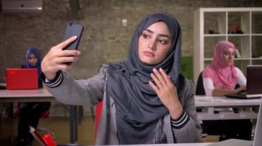 Çok güzel Arap kadın masaüstü ve alma selfie ciddi sakin bak, türban ve İslam görünümü, modern şık kadın, tuğla studio, içinde oturuyor