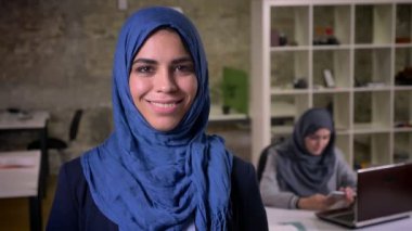 Arap kadın koyu mavi hijab ayakta modern ofis, günümüzde gerçeklik karşısında gülümsemek odaklı