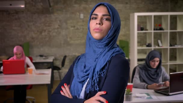 交差し カメラの点滅ではなく 事務所の図 女性を見て彼女の手で つの側面になって立っている青いヒジャーブを身に着けているアラブの女性の驚くべき平静な顔つき — ストック動画