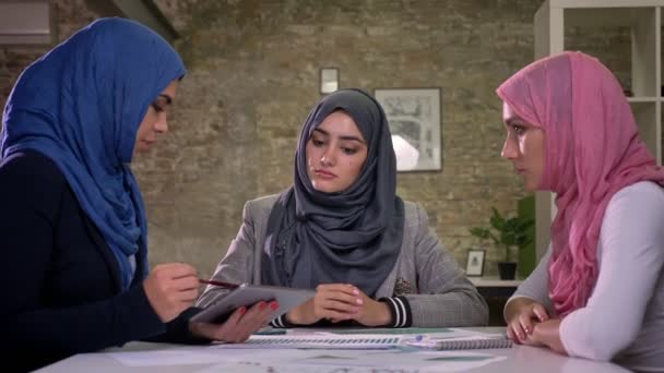 Três meninas árabe hijab estão sentados todos juntos em grande teble e falando com os pacientes sobre o trabalho, ilustração do escritório — Vídeo de Stock