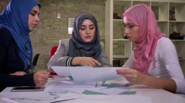 Muhteşem üç Arap kadın hep birlikte ortak masaüstü oturan ve notlar tartışmak ve iş konu hakkında Ortadoğu illüstrasyon günümüzde konuşuyor