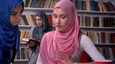 Güzel Arap kadın söz ve birlikte masada oturan, konuşmayı, hijab, Orta Doğu kız okuma kitabı arka plan üzerinde giyen