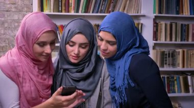 Müthiş kız hijab giyen seyir telefon ve Kütüphane, Ortadoğu illüstrasyon birlikte dururken gülümseyen