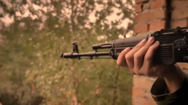 Yakın çekim silah silah, beyaz asker amaç holding silah süre ile el bakıyor, tuğla ev, boş bulutlu görünüm terk