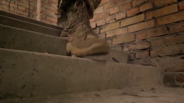 Prise de vue rapprochée ciblée des jambes en camouflage, l'homme militaire marche, escaliers, plancher intérieur — Video