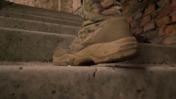 Close-up pés em botas de oficial andando no andar de cima no fundo de tijolo, camuflado cara interior — Vídeo de Stock