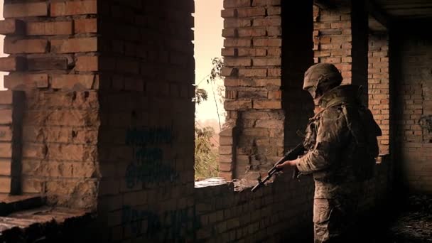 迷彩服で希望に満ちた強い戦士は自動銃を保持していると立っているレンガを放棄した背景の建物、前に太陽を見て上に分離 — ストック動画