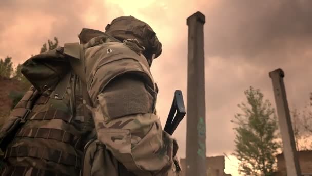 Starker kaukasischer Offizier in Tarnkleidung, der uns allein durch ein verlassenes Gebäude führt, Waffe in der Hand, mit kraftvollem Blick nach vorn blickend, bewölktes Wetter — Stockvideo