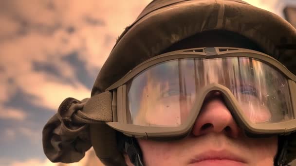 Close-up rosto de soldado caucasiano no capacete com céu e sol reflexão sobre óculos olhando para frente, vibrações de esperança e vida calma, autêntica — Vídeo de Stock