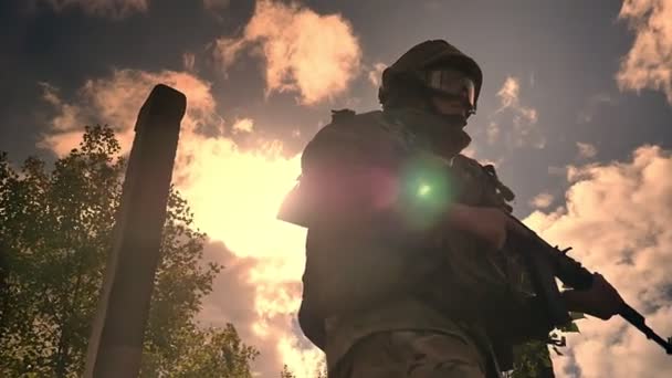 Resistente soldado caucásico sosteniendo ginebra automática está parado quieto, increíble vista de los cielos con sol el fondo, vista militar auténtica — Vídeos de Stock