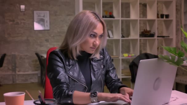 Kaukázusi szőke lány keres boldogan és képernyő-ból számítógép és bólogat büszkén belsejében könnyű modern office egyedül ülve a hideg kellemes arc — Stock videók