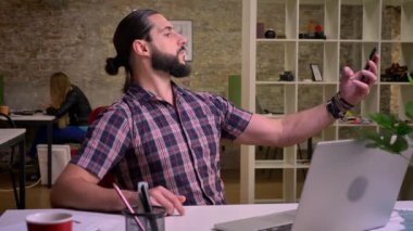 Sıradan görünümlü yakışıklı sakallı beyaz adam güzel selfies laptop ve tuğla ofis notlarda yakınındaki masasında otururken alıyor