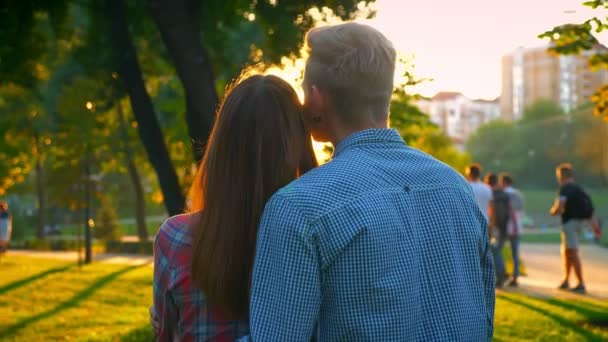 Tir de dos, beau couple caucasien se tenant l'un l'autre, debout et regardant vers l'avenir dans les rayons du soleil, arrière-plan du parc, extérieur — Video