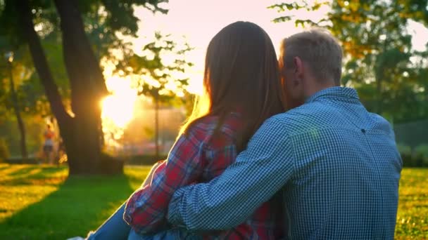 Casal encantador estão sentados na grama verde no estacionamento e segurando uns aos outros, momento inspirador juntos, fora da cidade rush — Vídeo de Stock