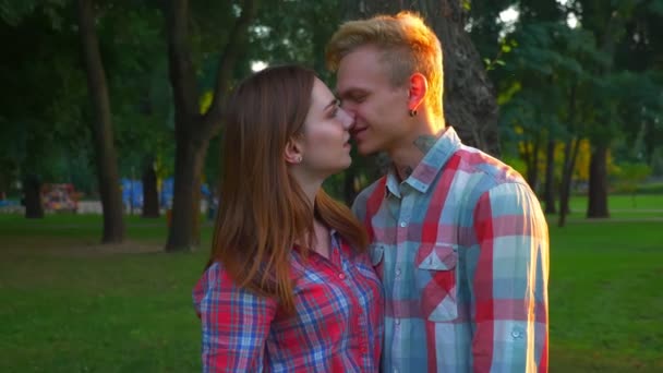 Hermosa pareja está pasando el rato en el parque de verano y besándose hacia la cámara, vibraciones encantadoras, imágenes alegres al aire libre — Vídeos de Stock