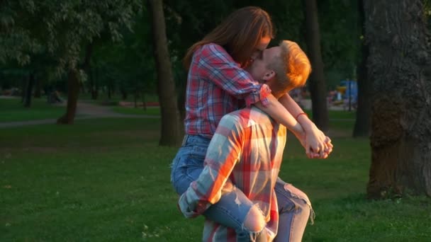 Great footage of love, boy is kissing his girlfriend and holding her with hands, turning on circle and moving in green park, fresh illustration, modern people — Stock Video