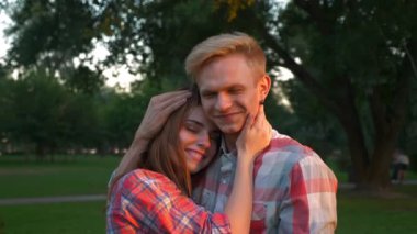 Rahat adam güzel saçlarını okşayarak ve onun omuz, güneşli park ve ağaçlar yakın, yaz mutluluk sarılma onun kız arkadaşı ile ayakta görüntüleri