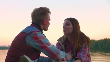 Taşlar üzerinde oturan ve birbirleri ile birlikte, an zevk konuşurken Nehri üzerinde arka plan, rahat tarzı, açık, güzel doğa güzel çift