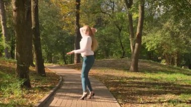 Muhteşem sarışın beyaz dansçı kız uzun saçlı Sunlights, mutluluk, keyifli, doğal görünüm, sincap parkında yolda dans ediyor