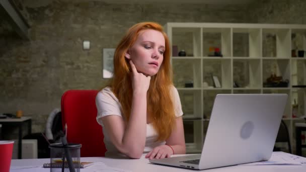 Schieten van doordachte gember Kaukasische vrouw, peinzen ontspannen en de juiste oplossing vinden zittend op haar werkplek indoor, productief — Stockvideo