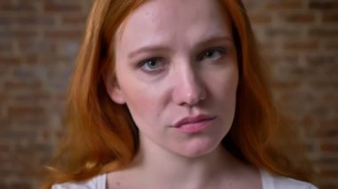 Sürpriz yüz geniş seyir oldukça zencefil beyaz kız ve mutlu bir şekilde kamera yakın çekim ve tuğla duvar rahat üzerinde ayakta