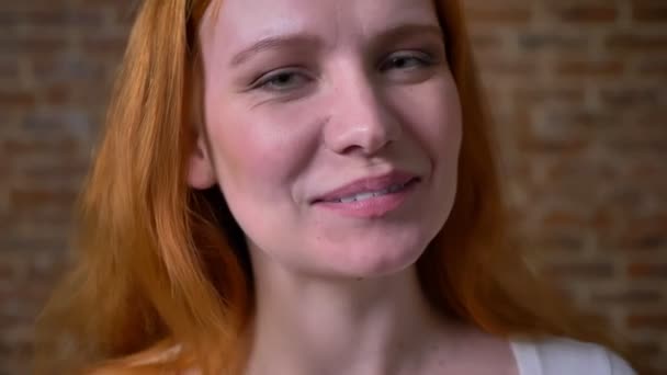 Jolie sourire amical de femme caucasienne roux, debout dans un studio brun clair, port décontracté et émotions artistiques à l'intérieur — Video