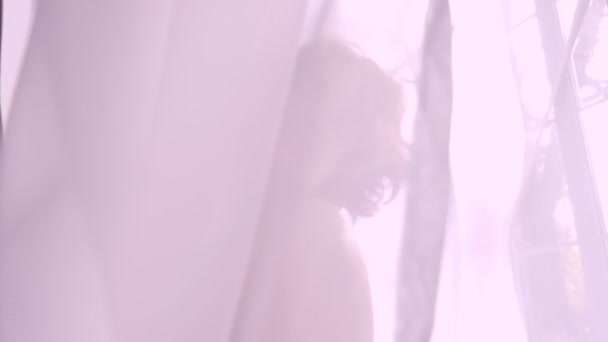 Ein kaukasisches Mädchen steht vor dem Fenster und lächelt in schwarzer Unterwäsche, Versuchung, Flirt, weißen Vorhängen und Tüll — Stockvideo