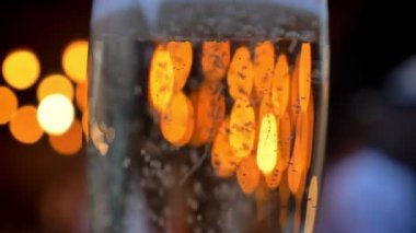 Arka planda, bokeh ışıklar yanıp sönüyor bardak köpüklü şampanya,