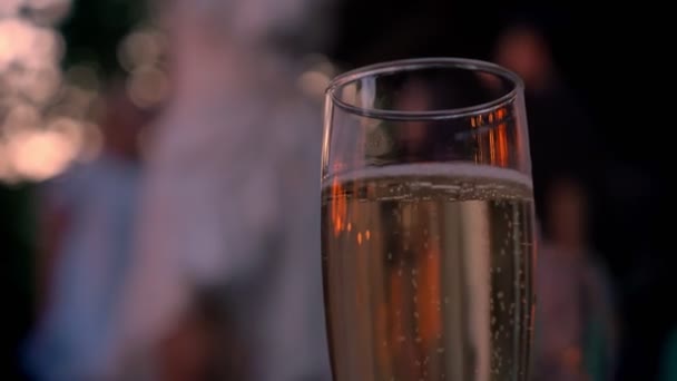 Copa de champán espumoso, gente bailando en el fondo, fiesta, bokeh — Vídeos de Stock