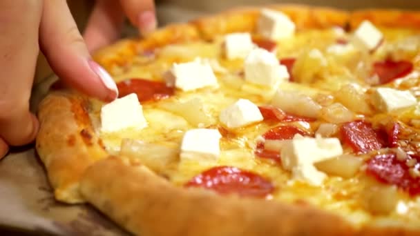 Gros plan délicieuse pizza est couché sur la table tandis que les mains séparent les tranches savoureuses avec du fromage et de la viande sur elle, restauration rapide — Video