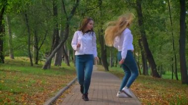 Beyaz muhteşem kızlar dans yolu yeşil güzel Park, en iyi arkadaşlar, yaz hava zevk ve güneşli bir gün, hareketli görüntüleri