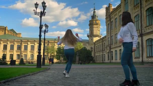 Hip-hop förflyttningar av kaukasiska vackra kvinnor dansar tillsammans tittar på kameran inspirerad med glada ansikten fortsätta att flytta, Utomhus, Univercity bakgrund — Stockvideo