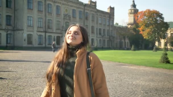 Glückliche kaukasische Frau steht und genießt Sonnenstrahlen auf ihrem Gesicht, schönes Wetter, Herbststimmung, lässig stilvolle Person stehend, in die Kamera blickend — Stockvideo