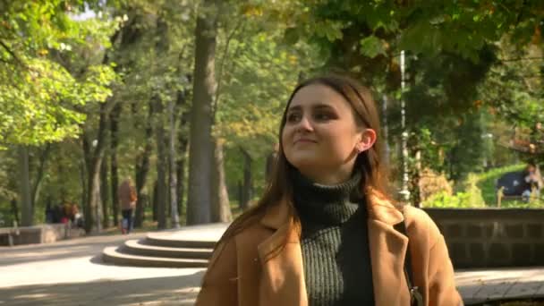 Footage of walking gorgeous caucasian woman is green nice park in sunshines, looking at trees and enjoying nice weather and nature — Stock Video