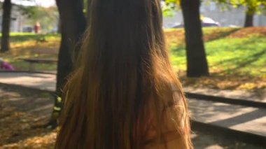 Uzun saçlı mutlu şaşırtıcı beyaz kız güneşe bakarak ve doğanın yeşil güzel park açık, resimde dururken yüzünde zevk