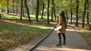 Güzel beyaz kadın yürüme rahat ve güneş, Park, mutlu bir şekilde ona vakit patika üzerinde yeşil ağaçların arkasında gizli bakarak ayakta rahatladın mı