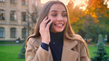 Güzel beyaz kadın telefon görüşmesinde geçiriyor, mutlu bir şekilde izole durmuş ise açık konuşuyorum rahat sakin ve kendinden emin, varlık kentsel güneşli arka plan