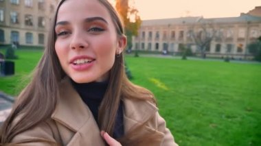 Duygusal sevimli beyaz kız mutlu vawing kamera olduğunu ve ayakta ve taşıma, yeşil güzel antik kent arka plan üzerinde doğal güzel manzara ile alarak video süre tutan