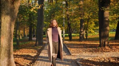 Park şaşırtıcı beyaz kadın kameraya doğru gidiyor soğuk ve park manzaralı mutlu ve rahat görünümlü, doğa açık, sunlights sonbahar zevk