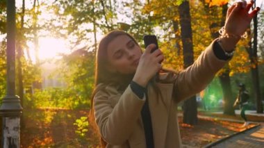 Oldukça kafkas kadın altın yaprak telefonda mutlu sonbahar havalarda güneşli park, modern rahat illüstrasyon ayakta iken resim alıyor