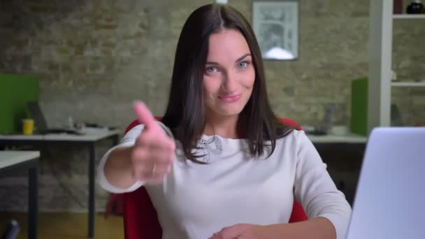 Деловая женщина в офисе смотрит в камеру и кладет палец вверх, чтобы показать, как и уважение — стоковое видео