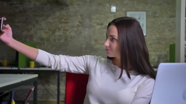 Vacker kvinna tar selfie foton med hjälp av sin smartphone i office — Stockvideo