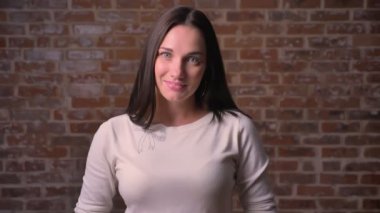 Kadın kameraya izliyor ve bir bricken arka plan üzerinde sert gülmeye başlar.