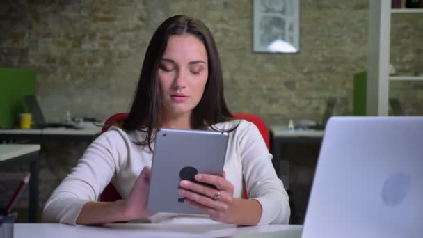 Imprenditrice lavora con attenzione con il tablet in ufficio — Video Stock